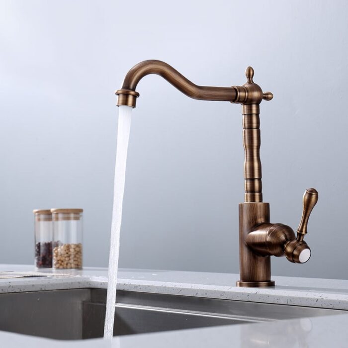 Brass kitchen faucet with a vintage design, pouring water over a sink.