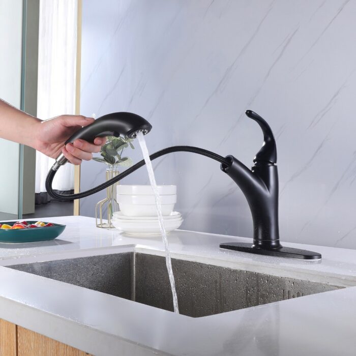 Modern black kitchen faucet with pull-down spray head, in use at a white countertop sink.