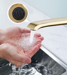 Water flow from modern gold faucet with filtration system, hands washing in kitchen sink.