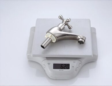 Stainless steel kitchen faucet on digital scale weighing 620 grams, modern plumbing fixture for homes and kitchens.