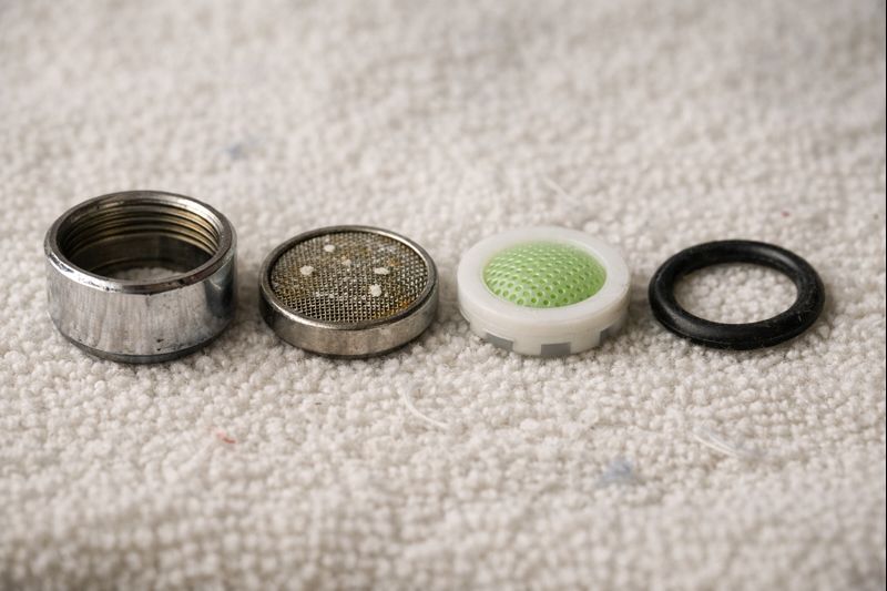 Como limpar um aerador de torneira (Guia 2026) 4 Faucet aerator parts laid out in order on a towel for easy reassembly