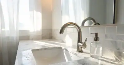 Close-up of a sleek kitchen sink with A-Torneira faucet and marble countertop.