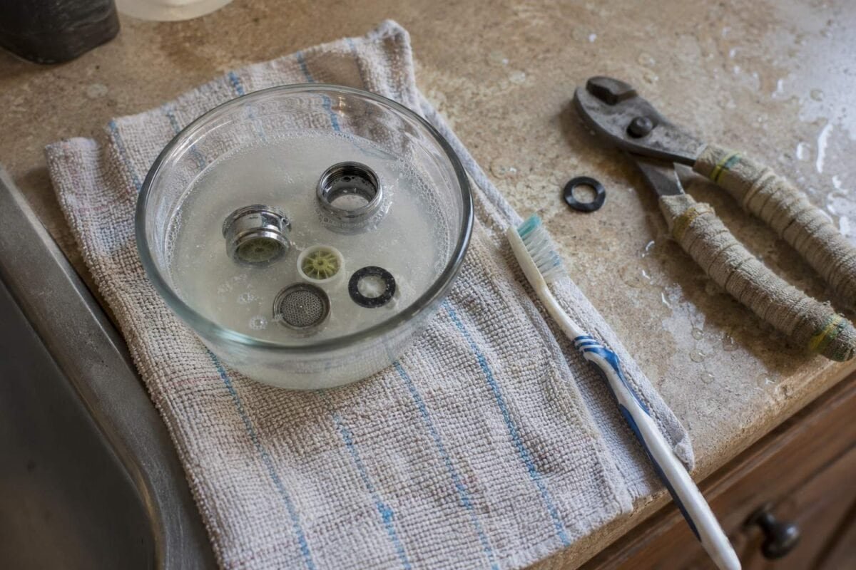 Faucet aerator parts soaking in white vinegar before cleaning